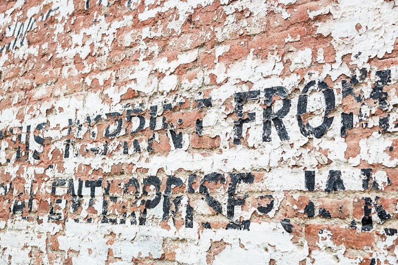 Old weathered brick wall with decaying advertisement writing