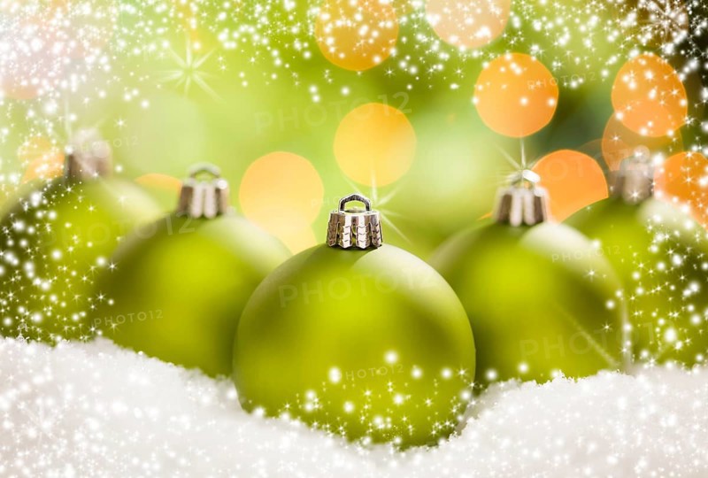 Beautiful matt green christmas ornaments on snow flakes over an abstract snow and light background with room for your own text