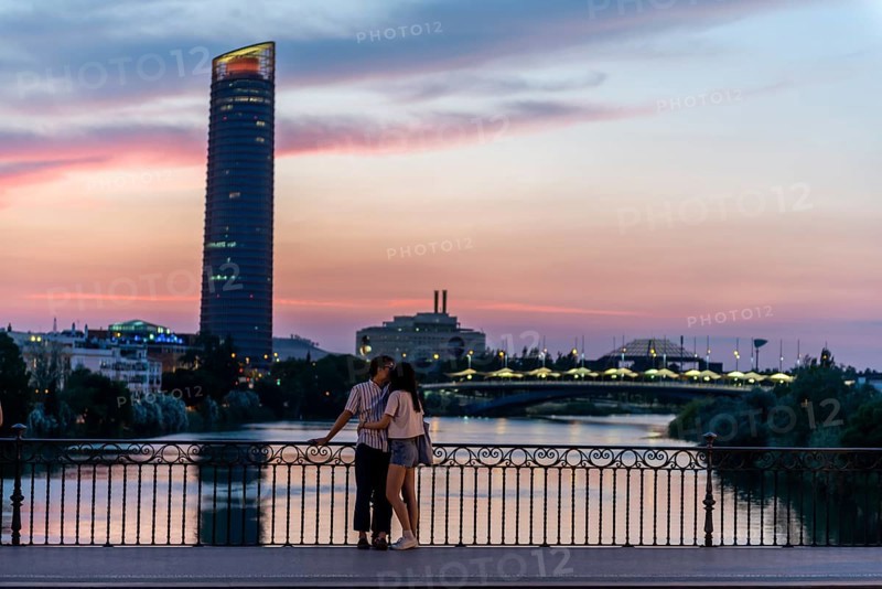 Couple standing on the bridge at sunset and kissing