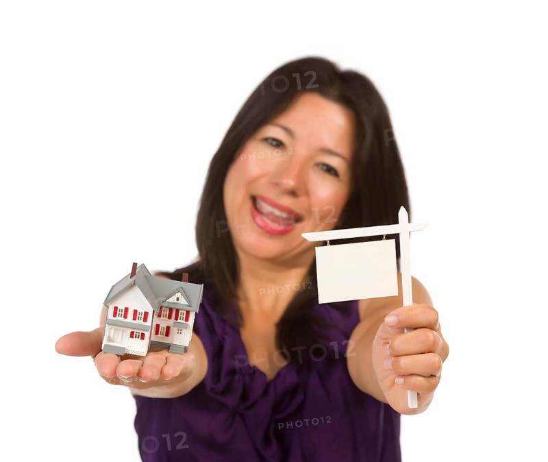 Multiethnic woman holding small blank real estate sign and house in hand isolated on white background