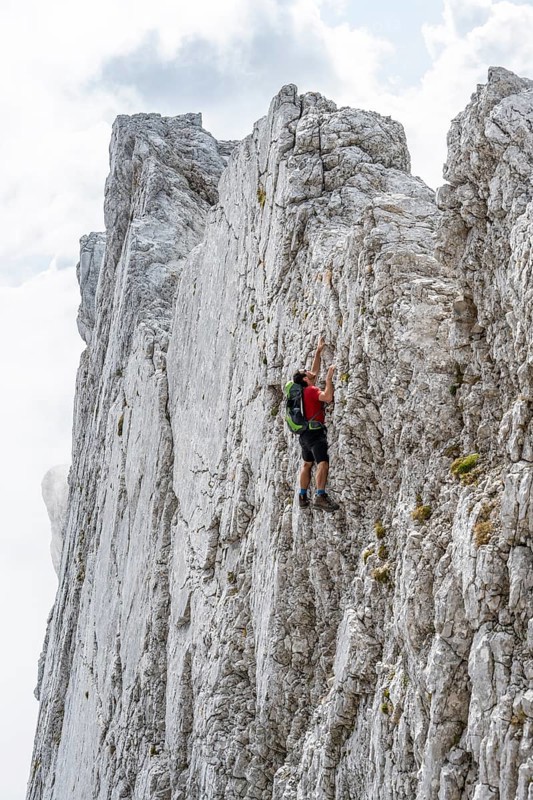 Young man climbing a vertical rock face without a rope