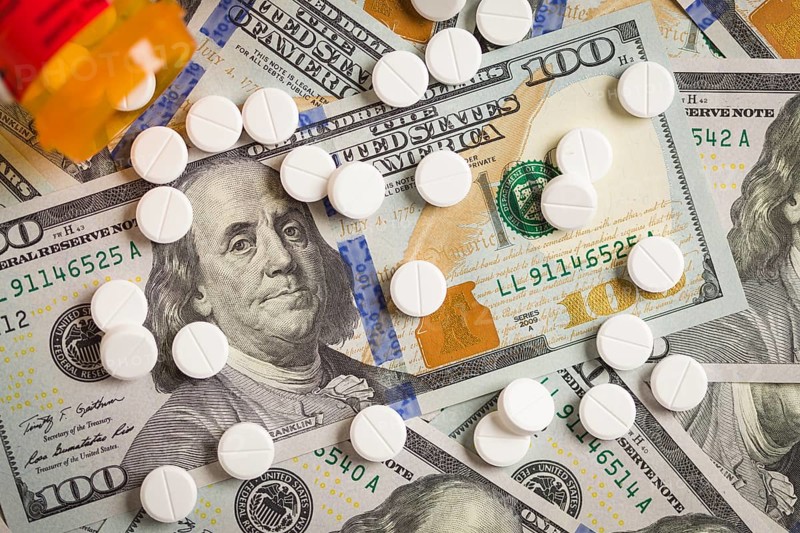 Medicine pills scattered on newly designed U.S. one hundred dollar bills