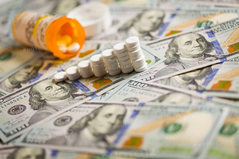 Medicine pills stacked like increasing graph on newly designed U.S. one hundred dollar bills