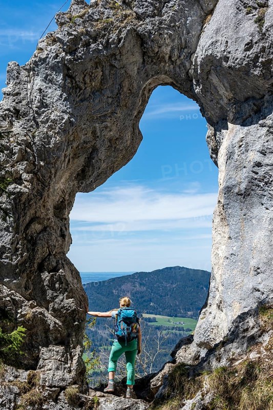 Hiker standing in the rock gate Breitensteinfensterl with view of high fog over the valley