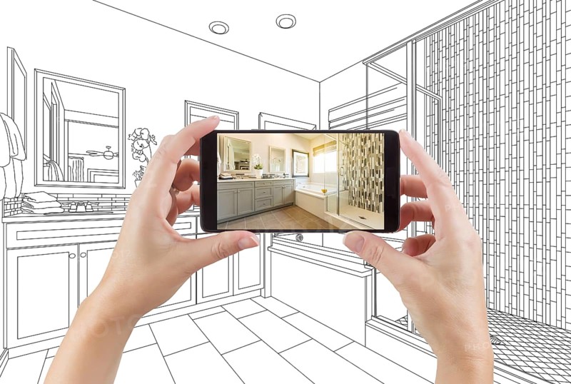 Hands holding smart phone with master bathroom photo on screen and drawing behind