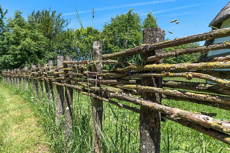Wooden fence connected with thin branches in wickerwork