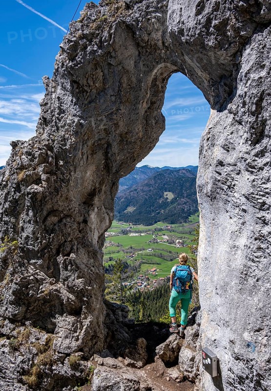 Hiker standing in the rock gate Breitensteinfensterl with view of high fog over the valley