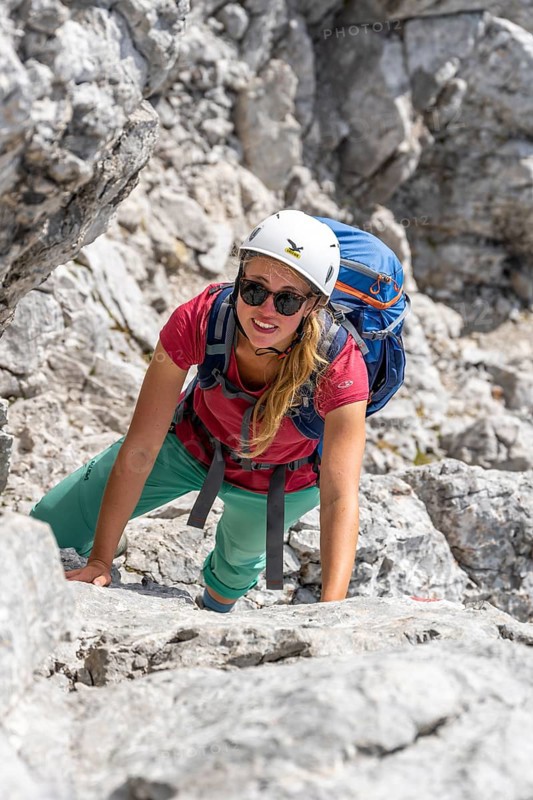 Young female hiker climbing with helmet