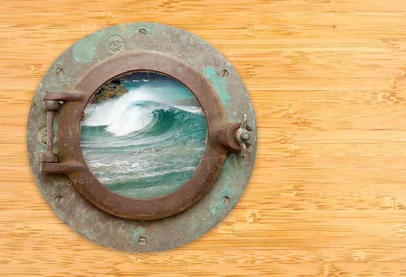 Antique porthole with view of crashing waves on a bamboo wall background