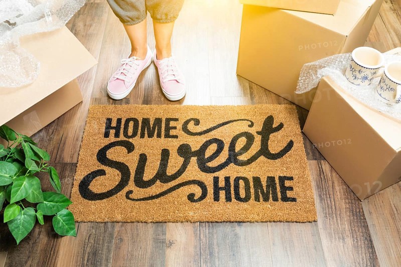 Woman in pink shoes and sweats standing near home sweet home welcome mat