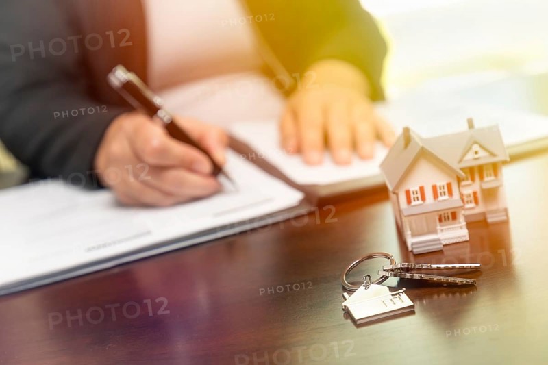 Woman signing real estate contract papers with house keys