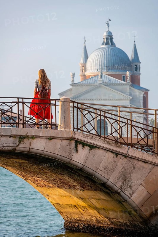 Young woman in red dress on a bridge at a canal