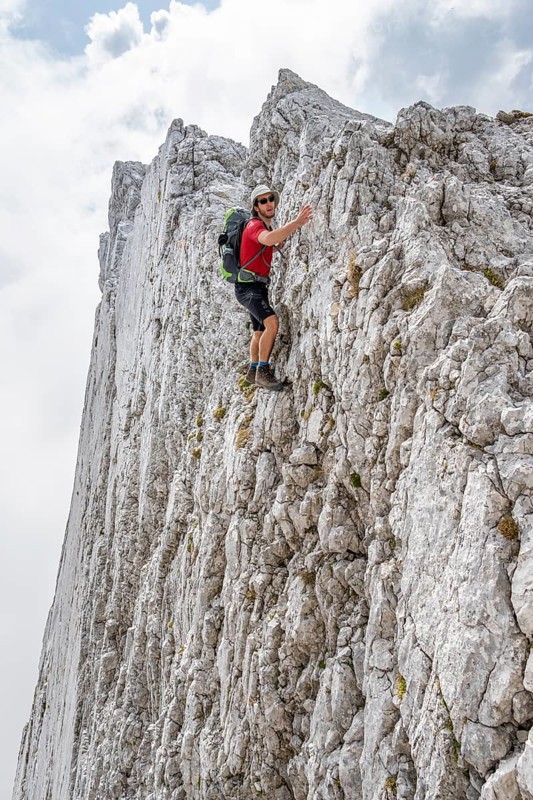 Young man climbing a vertical rock face without a rope