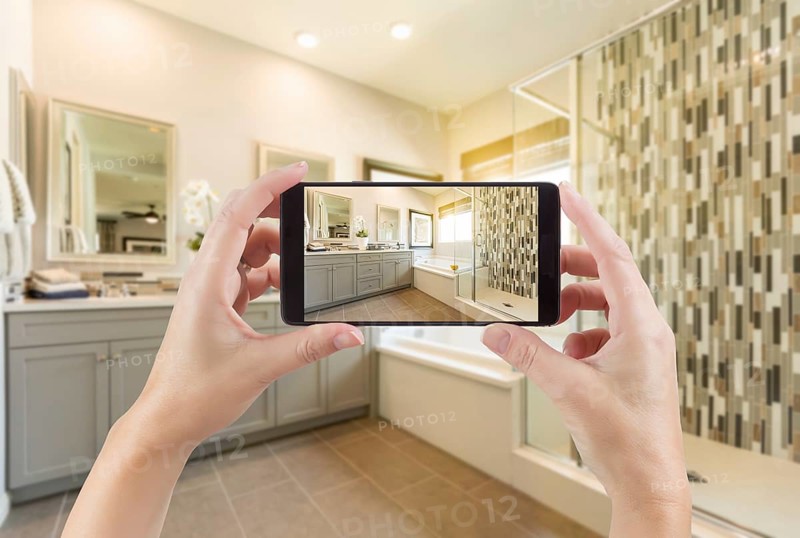 Master bathroom interior and hands holding smart phone with photo on screen