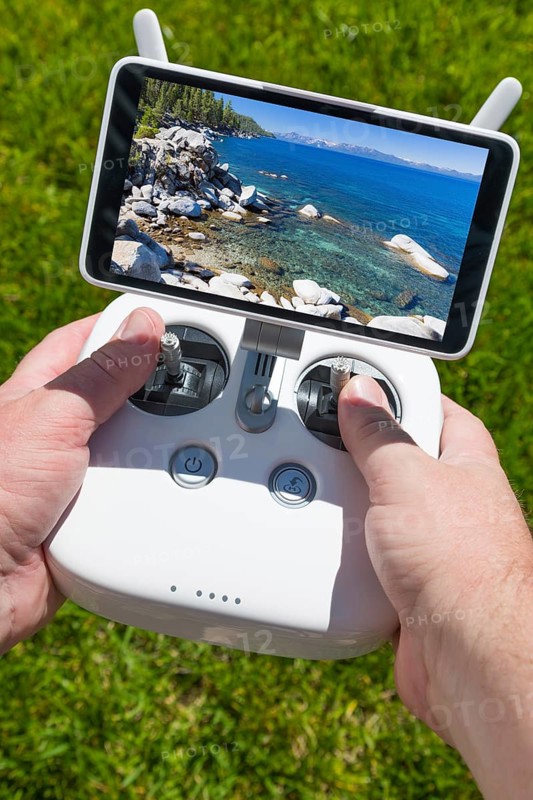 Hands holding drone quadcopter controller with beautiful lake view on screen