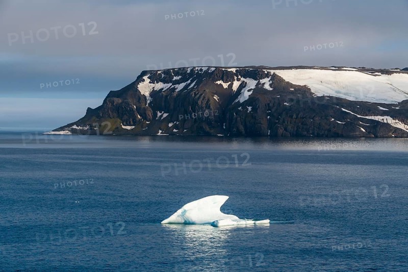 Iceberg floating before the flat table mountains covered with ice
