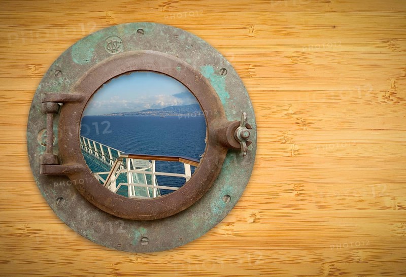 Antique porthole on bamboo wall with view of ship deck railing