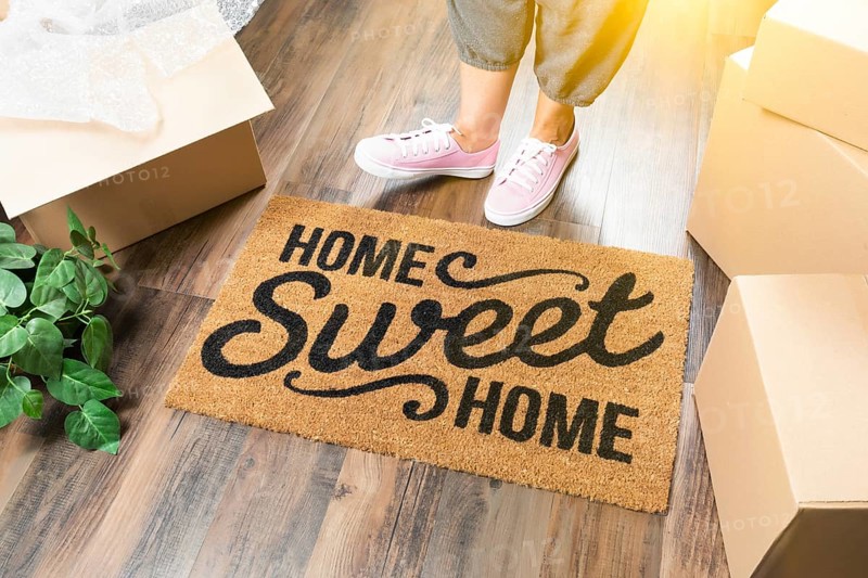 Woman in pink shoes and sweats standing near home sweet home welcome mat