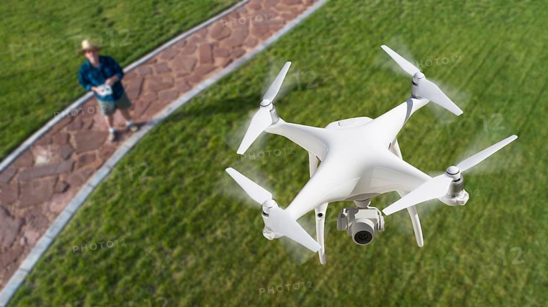 Drone quadcopter (UAV) in air above pilot with remote controller