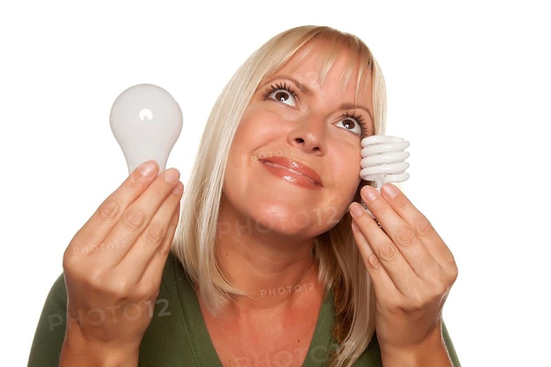 Smiling woman holds energy saving and regular light bulbs isolated on a white background