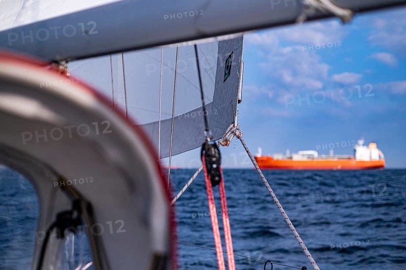 Sailing on the North Sea near Holland with freighter at anchor