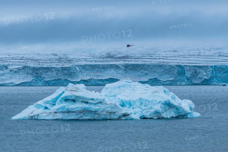 Helicopter flying over a very huge glacier on Mc Clintok or Klintok Island