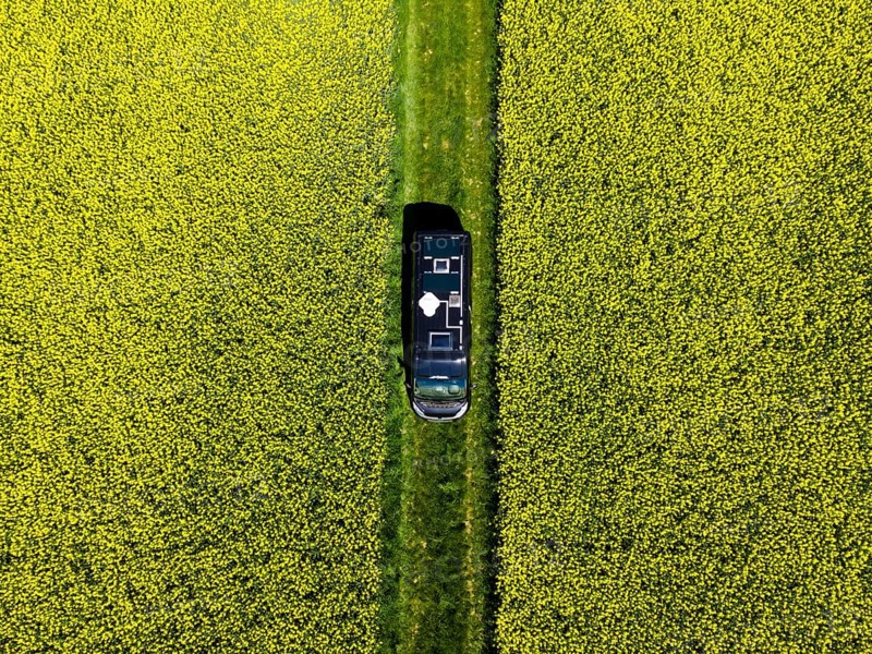 Drone shot of a camper van in a rape field