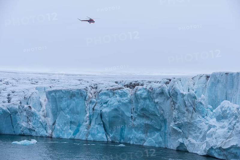 Helicopter flying over a very huge glacier on Mc Clintok or Klintok Island