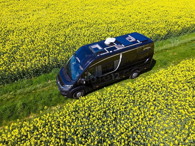 Drone shot of a camper van in a rape field