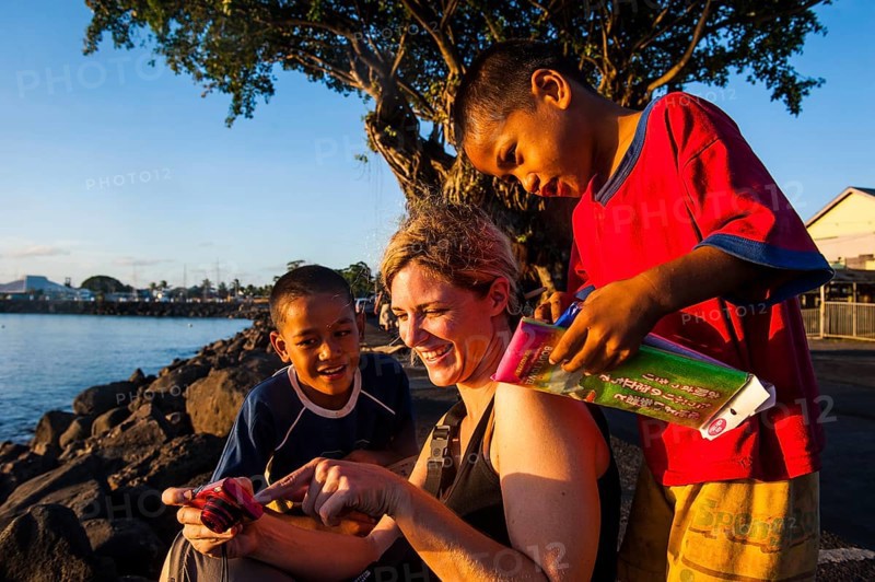Western woman showing photos on a digi cam to local boys