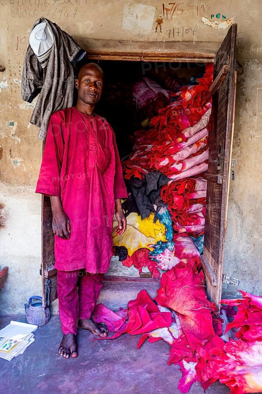 Shopkeeper before his shop full of colourful leather