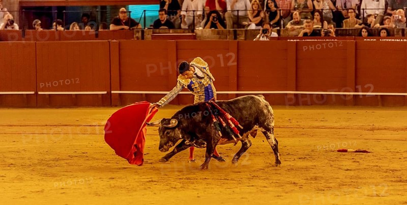 Matador with muleta and espada with running bull