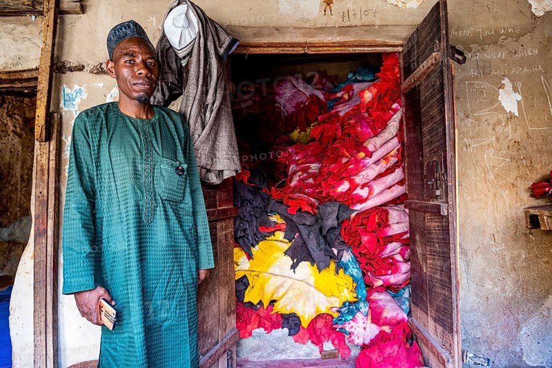 Shopkeeper before his shop full of colourful leather