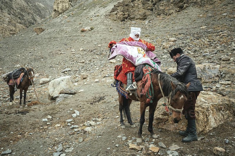 A man helps his pregnant woman onto a horse