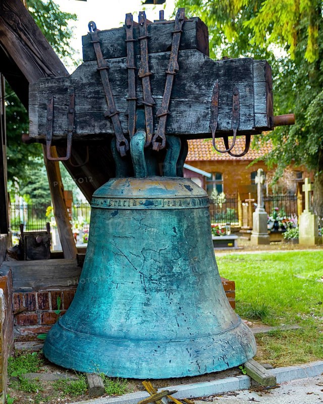 A belfry standing on the ground with four bells of different sizes in the village of Miloradz