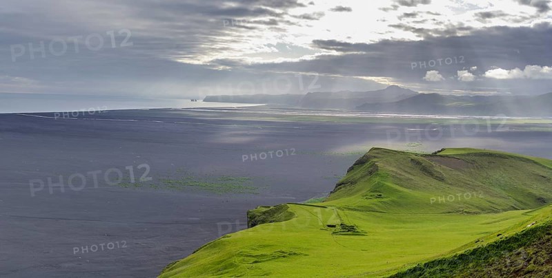 Old farmstead at Hjoerleifshoefdi (Viking grave) behind wide lava sand area and the Reynisdrangar