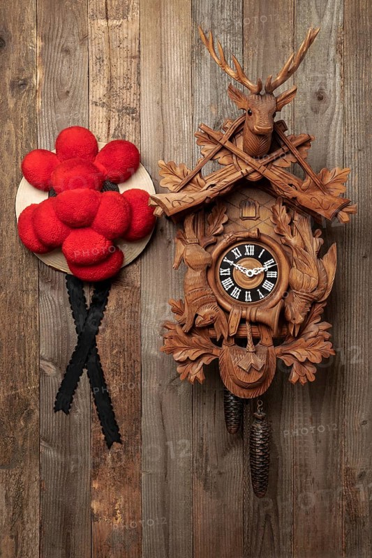 Original Black Forest cuckoo clock and Bollen hat in front of rustic wooden wall