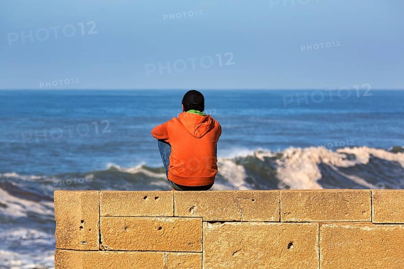 Young man sitting on the city wall