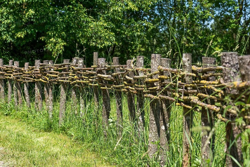 Wooden fence connected with thin branches in wickerwork