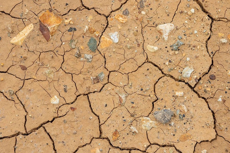 Cracks in the clay soil and coloured rhyolite rock