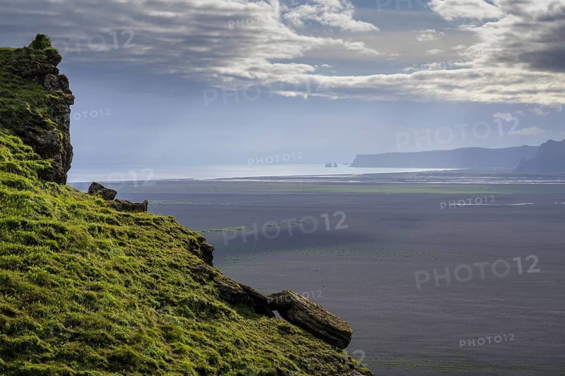 View from Hjoerleifshoefdi (Viking grave) across wide expanse of lava sand to Reynisdrangar