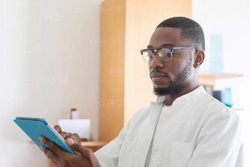 Young black doctor with smock and tablet