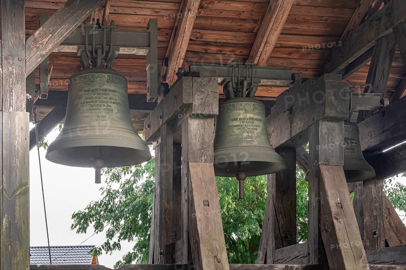 A belfry standing on the ground with four bells of different sizes in the village of Miloradz