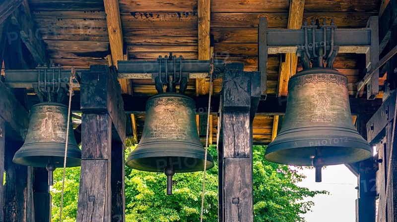 A belfry standing on the ground with four bells of different sizes in the village of Miloradz