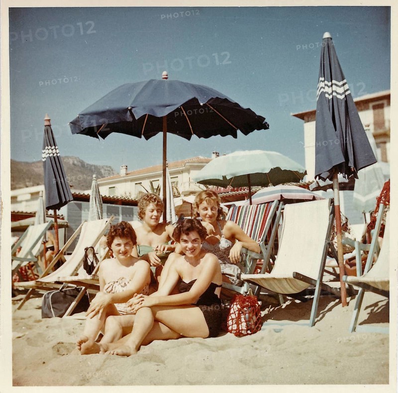 Four young German holidaymakers sitting on the beach of Finale Ligure