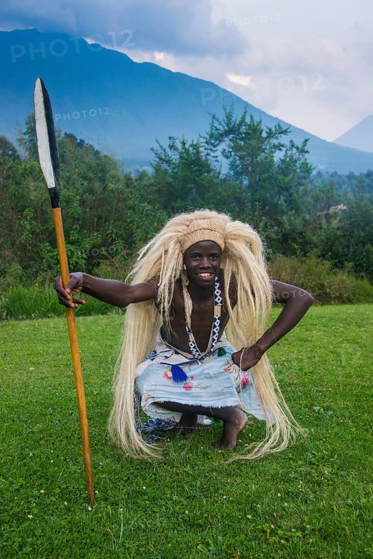 Man wears a wig carries a spear at a ceremony of former poachers