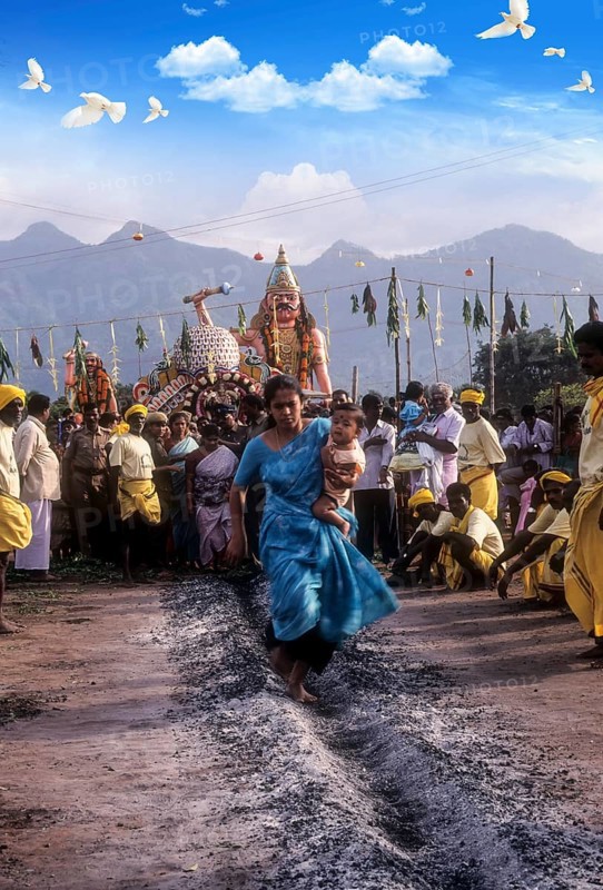 A woman carrying a child on her hip and running on burning coal