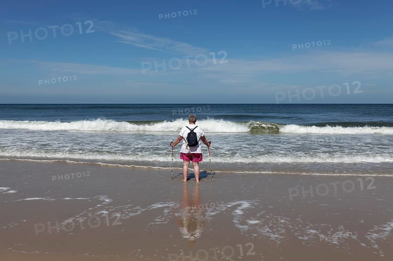 Lone beach walker looking out to sea
