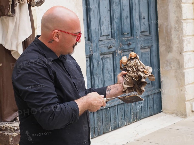 Artist creates a statue of a saint in the traditional way