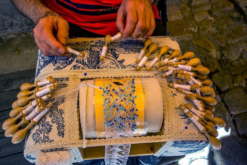 Man making traditional French lace before his shop